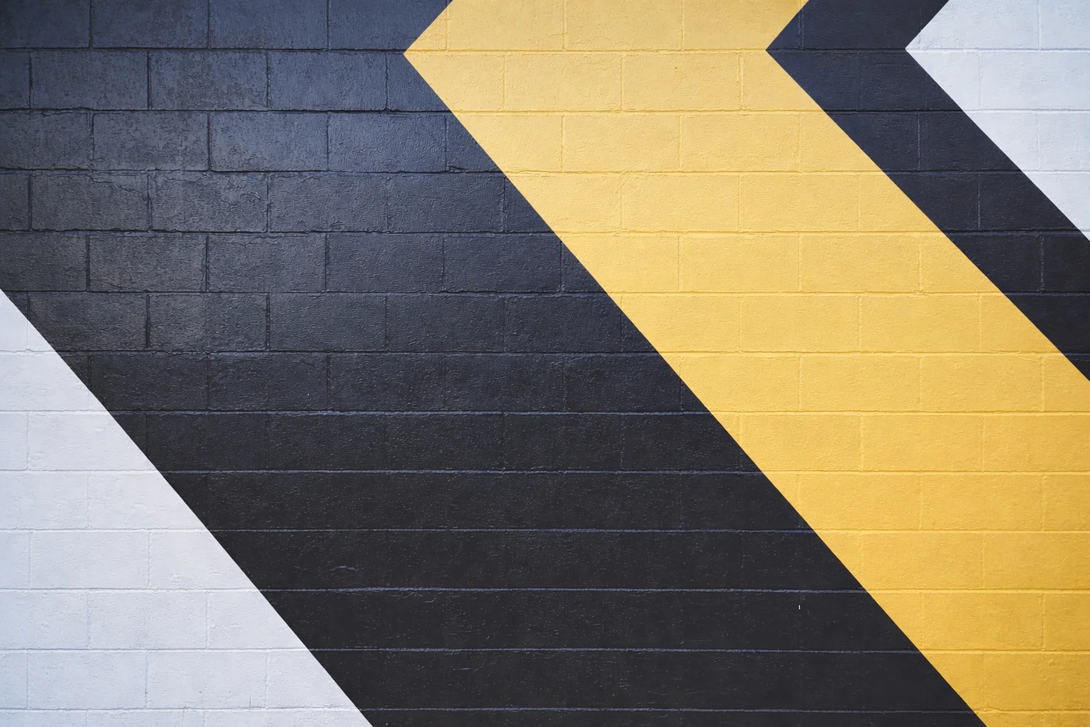 Pared de
            ladrillos pintada de blanco, negro y amarillo.
